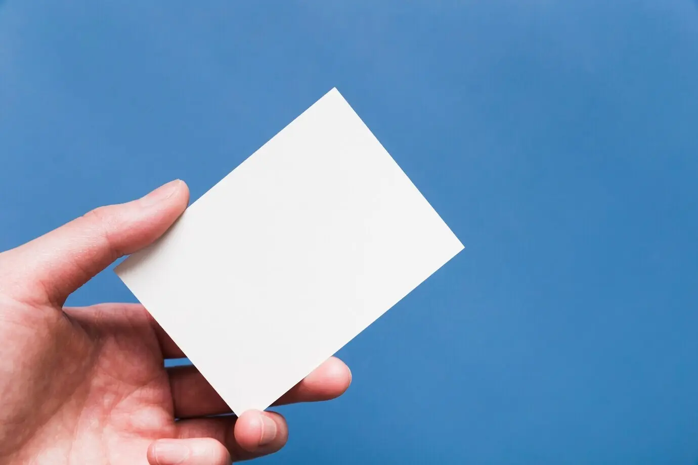 Крупный план руки, держащей белую визитную карточку.